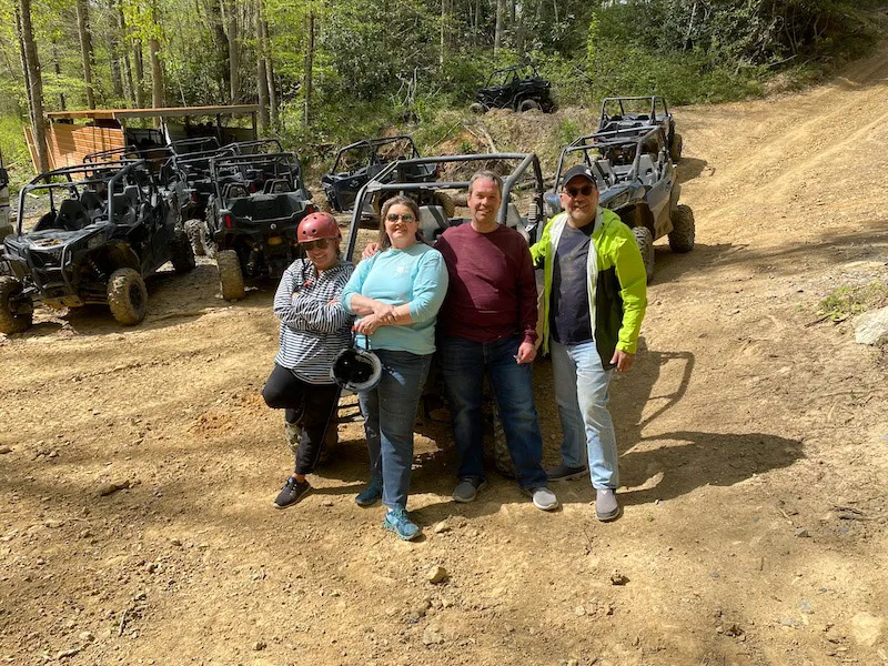 A family of four in front of the row of parked UTVs