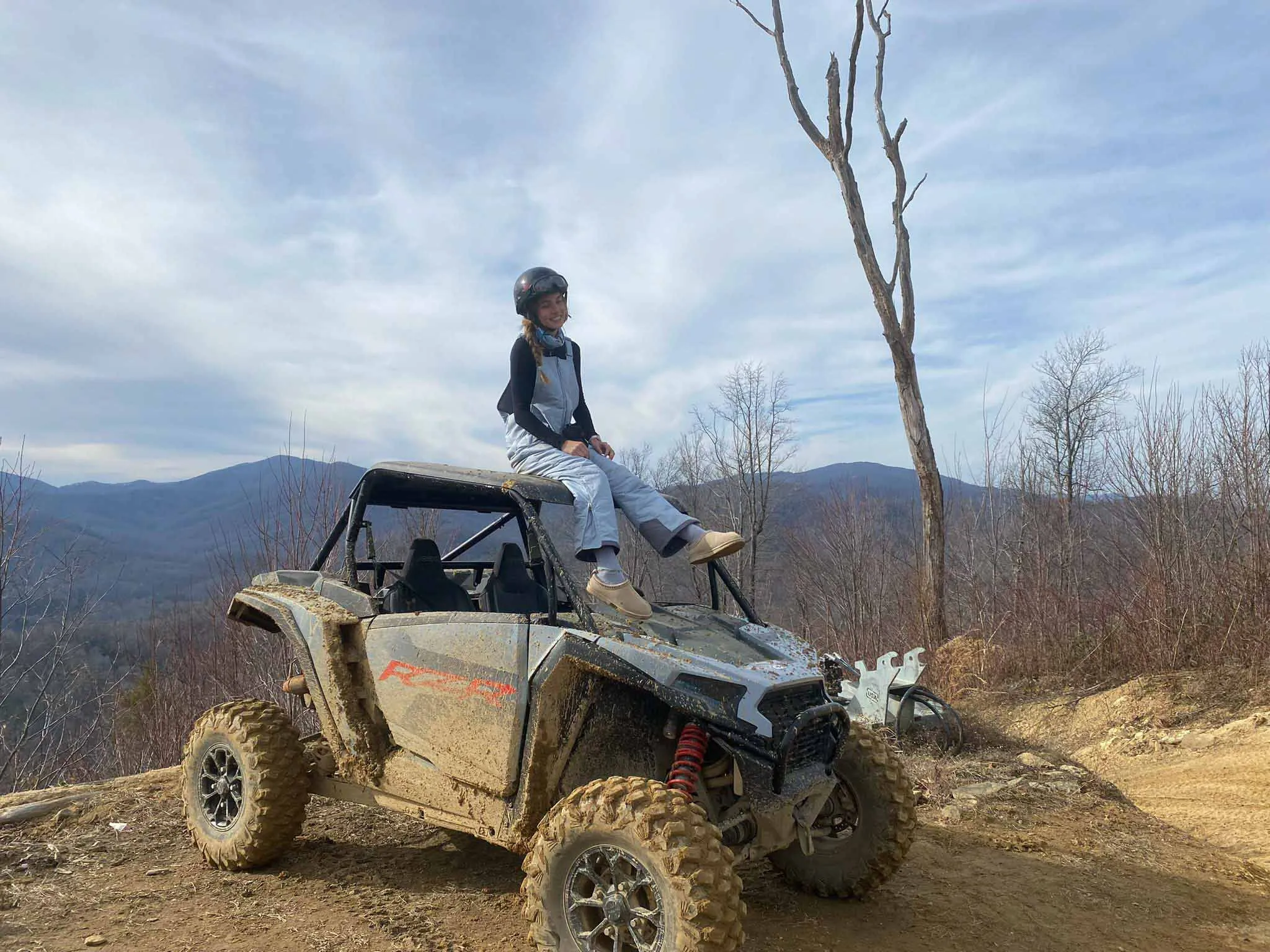 A child sitting on the hood of a UTV at the mountain overlook