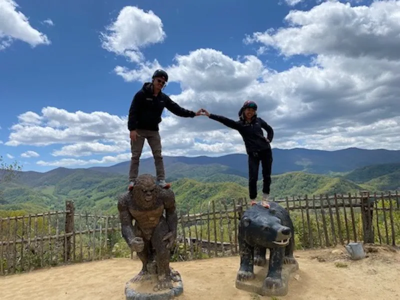 Two people standing on the bear sculptures shaking hands, the valley behind them