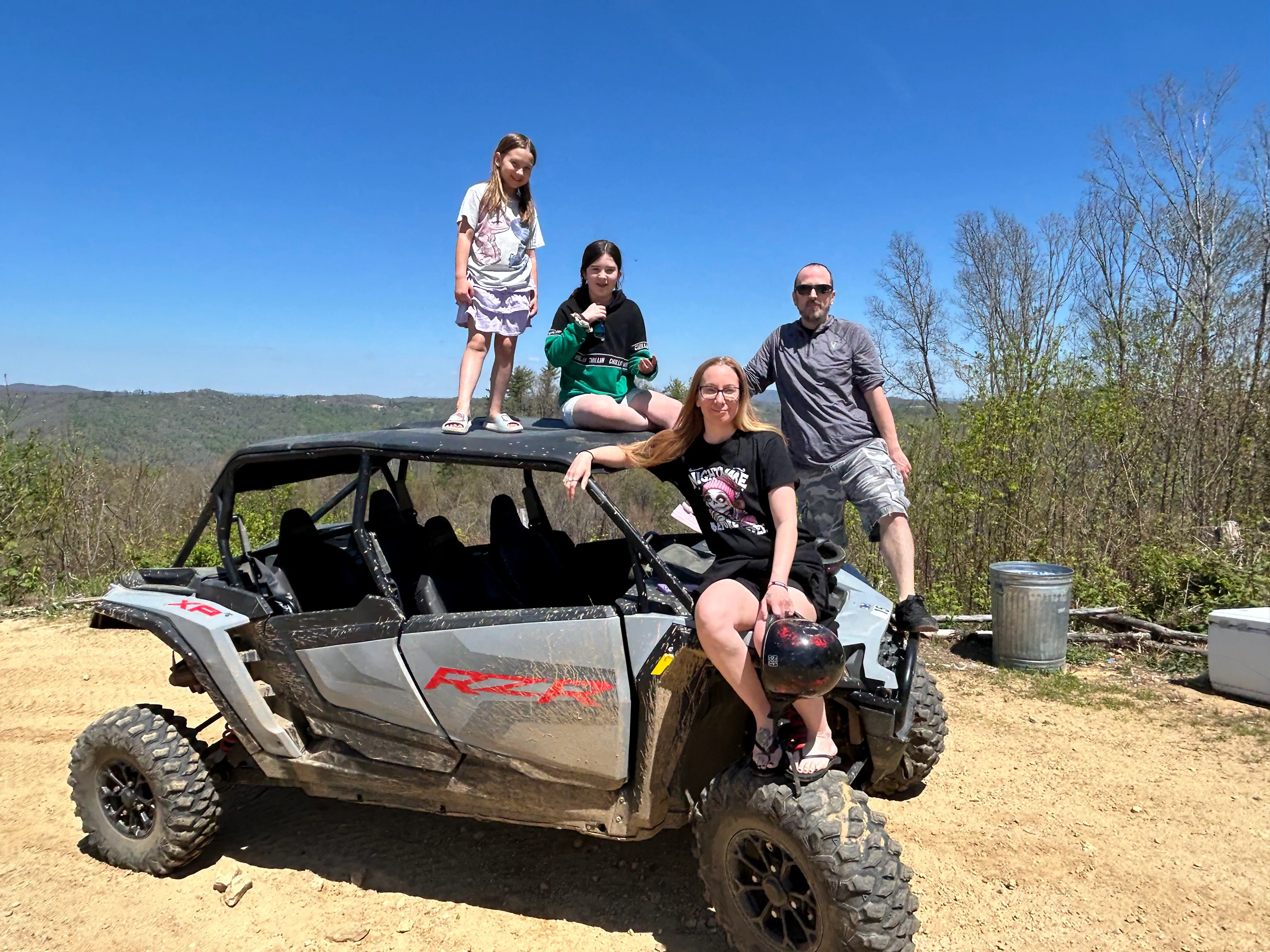 A family posing on a Polaris RZR at a mountain overlook in the Appalachians