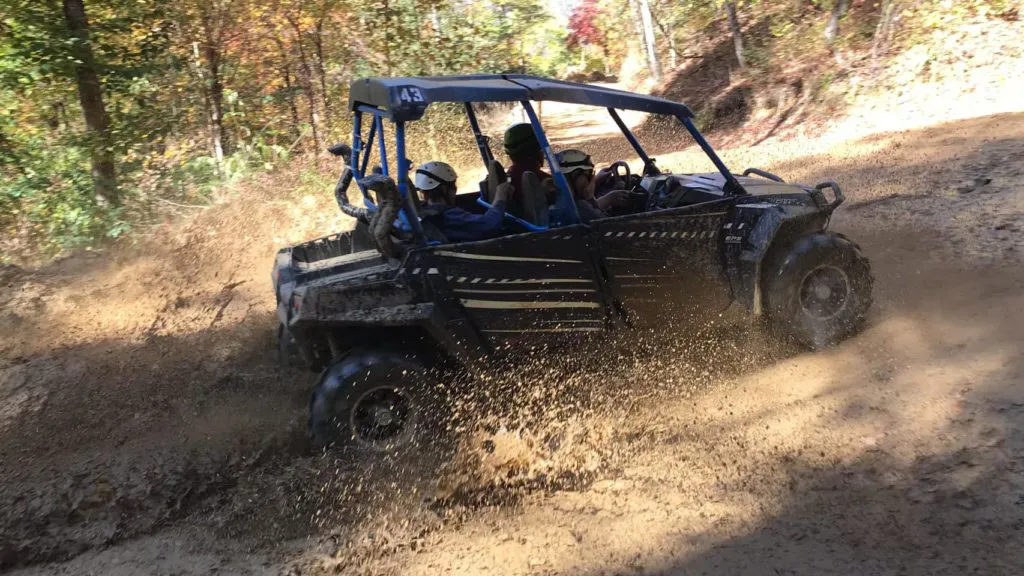 A UTV throwing up mud through a bend on the mountain trail