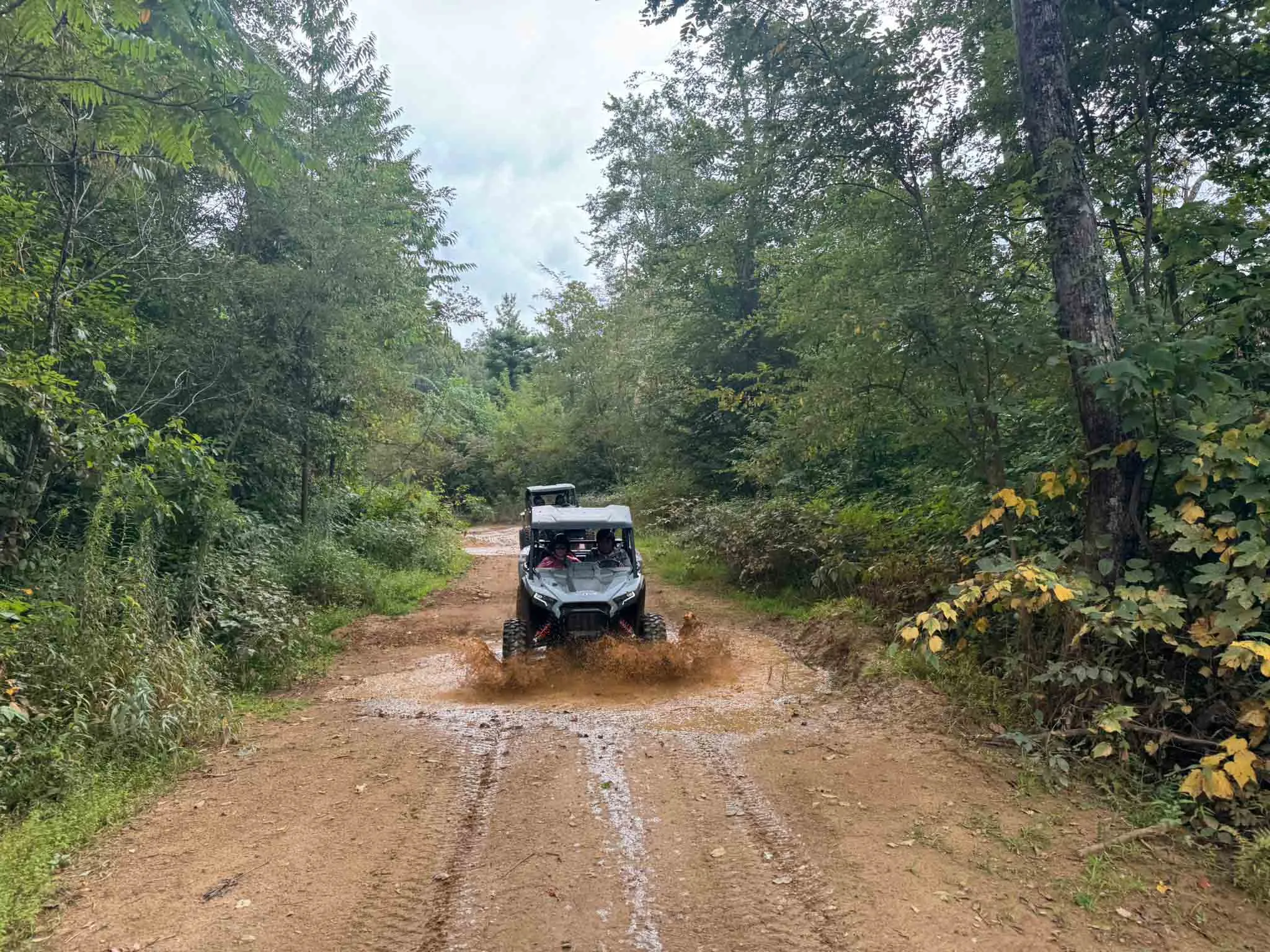 A UTV throwing mud as it powers down a wet forest trail in the High Country